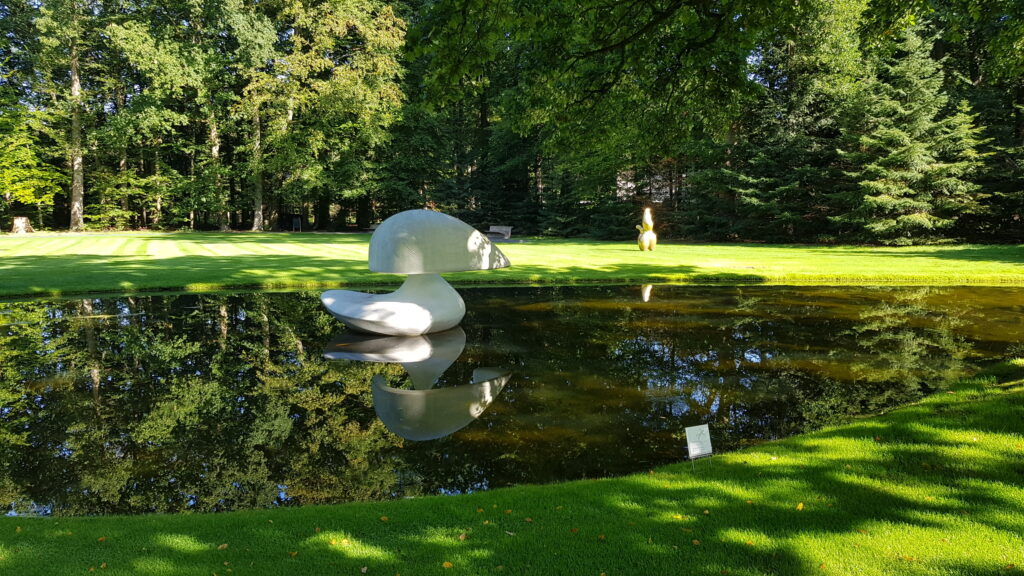 A floating sculpture of two opposing hemispheres floating in a pond.